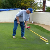 worker adding top dressing to the infill