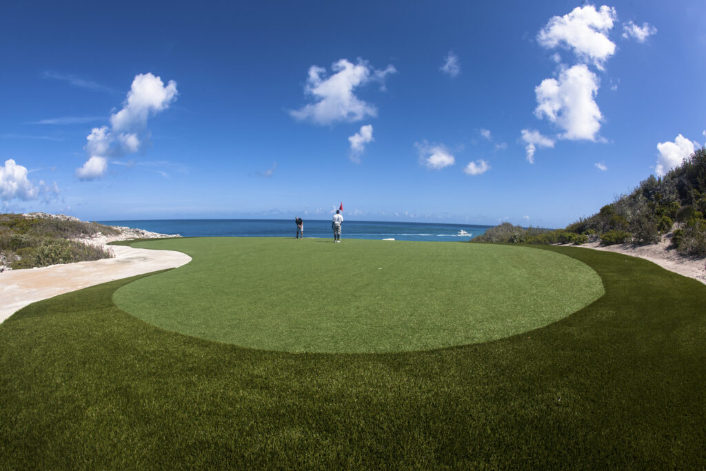 golfers on a green overlooking the sea