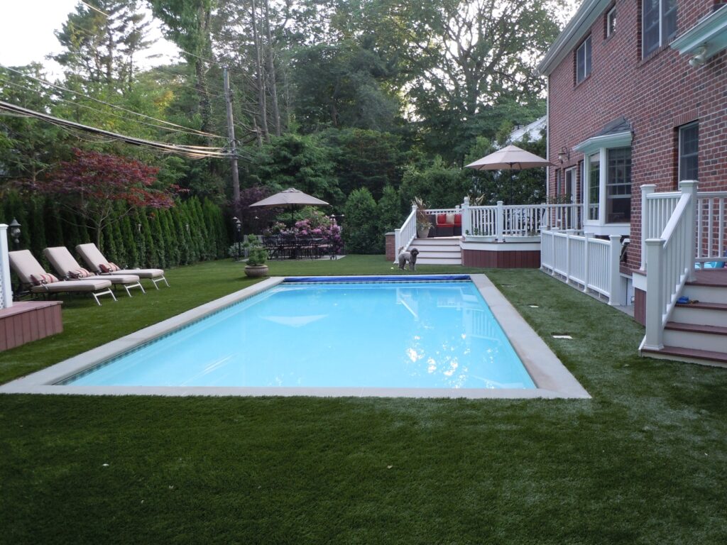 Synthetic turf surrounding a pool in a backyard