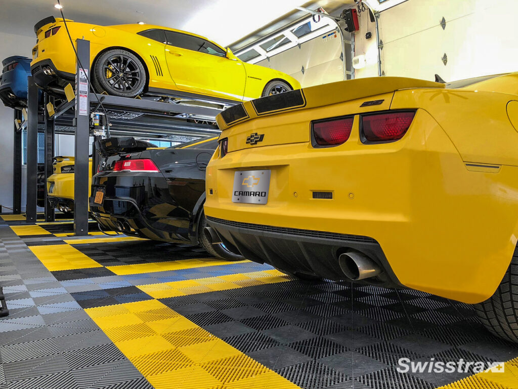multiple sports cars parked in a large garage with swisstrax flooring