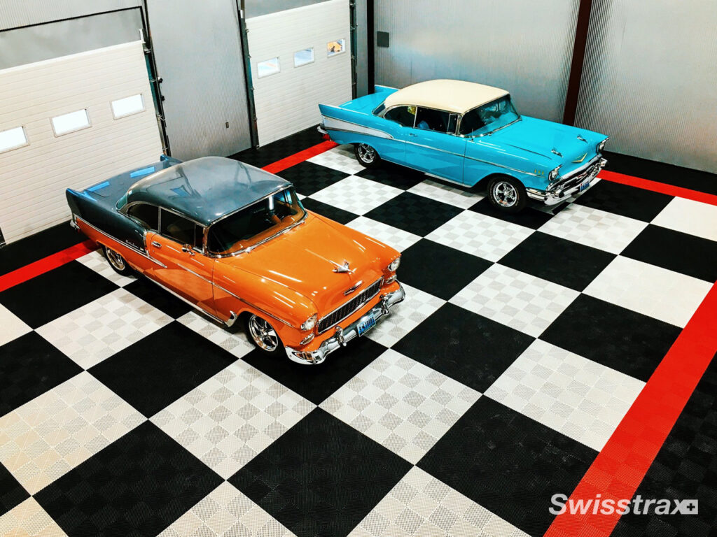 two vintage cars parked in a large garage with colorful swisstrax flooring