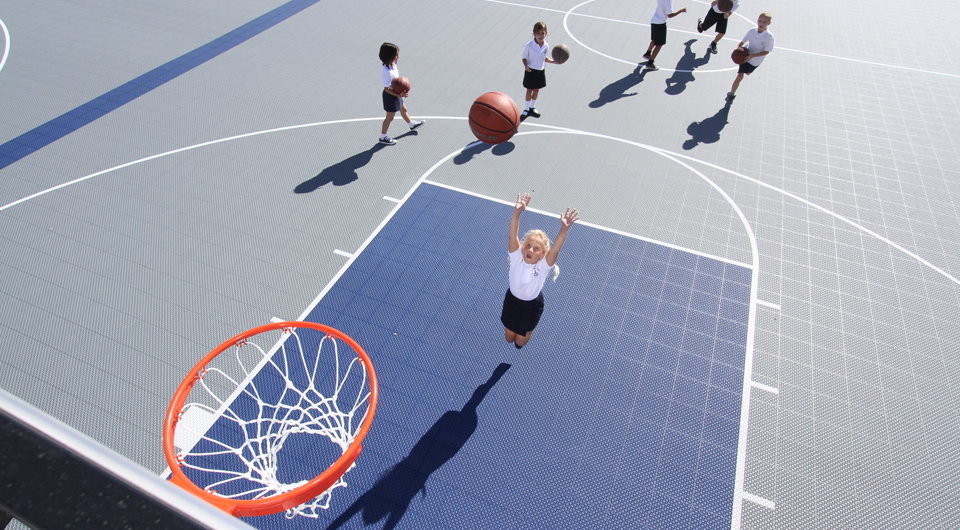 little girl shooting a basketball on a versacourt at school